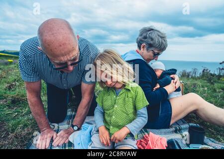 Großeltern mit Vorschulkinder und Baby genießen ein Picknick auf einer Wiese Stockfoto