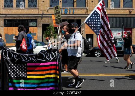 Regenbogen amerikanische Flagge, die sagt "Wir das Volk" und Protestler mit Flagge auf dem Kopf auf März gegen Trump's Police State, Washington, DC, USA Stockfoto