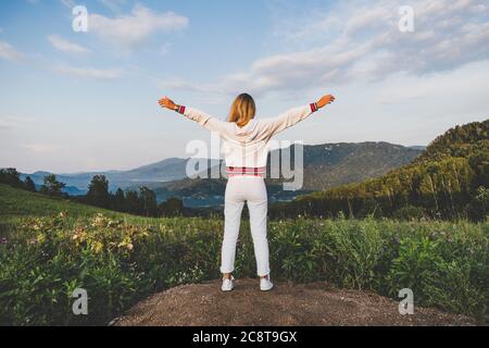 Fitness, Sport, Peop und Emotionen Konzept, glückliche Frau in Sportbekleidung genießen Freiheit über Berge und blauen Himmel Hintergrund. Rückansicht auf der Rückseite Stockfoto