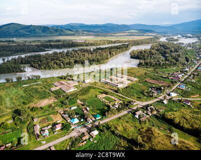 Dorf in Russland, Altai-Gebirge, Häuser und Katun-Fluss. Draufsicht auf den Gebirgsfluss im Altai-Gebirge und das Dorf Aya. Altai-Gebiet. Stockfoto