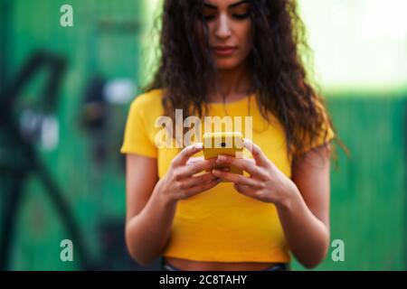 Junge Araberin, die mit ihrem Smartphone auf der Straße spazieren ging Stockfoto