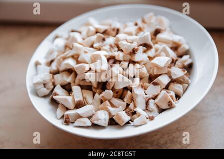 Frisch geschnittene Champignon-Pilze auf einem weißen Teller. Stockfoto