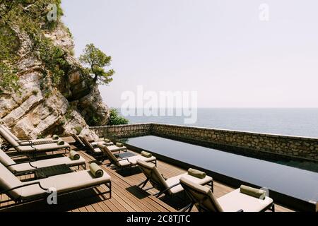 Sonnenliege am Pool auf der Insel Sveti Stefan mit Blick auf das Meer. Stockfoto