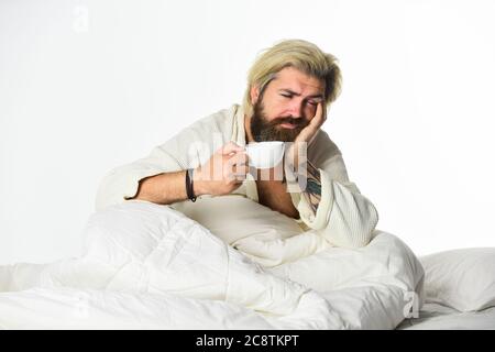 Schöner Mann trinkt Kaffee. Reifer bärtiger Mann im Bett. Der Körper wurde von wesentlichen Komponenten für eine gute Gesundheit und Energie beraubt. Start Tag mit gutem Kaffee. Gourmet-Espresso. Genießen Sie morgens Kaffee. Stockfoto