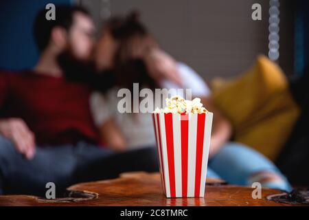 Ein junges Paar in Liebe Fernsehen in der Nacht romantische Dattnacht auf der Couch liegend essen Popcorn Stockfoto