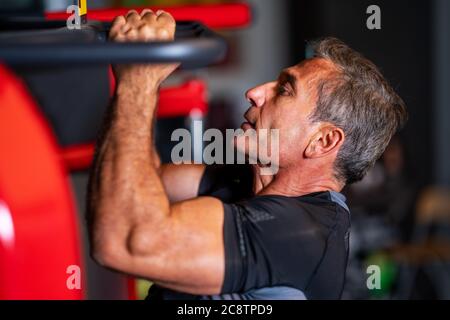 Mann stärkt seine Muskeln durch Pull-up auf horizontale Bar in einem Fitnesscenter. Hochwertige Fotos Stockfoto