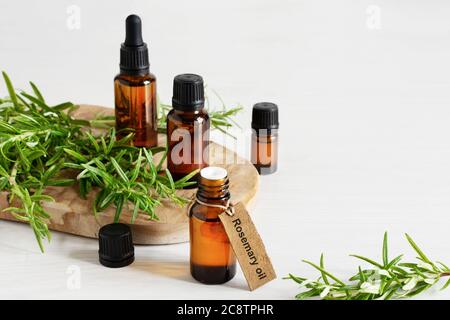 Töls aus Rosmarin ätherischem Öl und frischem Rosmarin Zweig auf weißem Holzgrund. Stockfoto