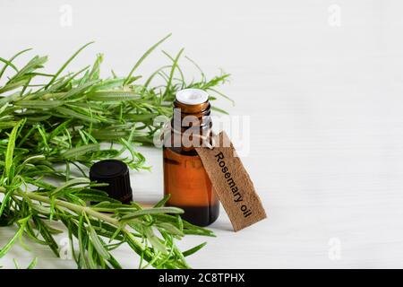 Töls aus Rosmarin ätherischem Öl und frischem Rosmarin Zweig auf weißem Holzgrund. Stockfoto