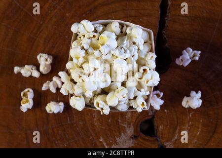 Popcorn in gestreifter retro rot-weißer Kartonschachtel für Kino auf Holztisch Stockfoto