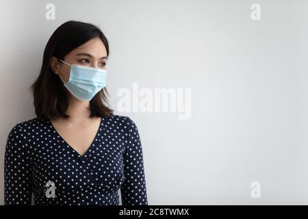 Nachdenkliche vietnamesische Frau in medizinischen Gesichtsmaske Blick in der Ferne Stockfoto