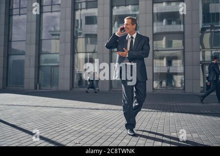 Fröhlicher Geschäftsmann, der auf der Straße telefoniert Stockfoto