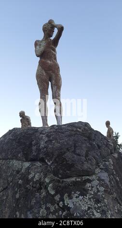 Vertikale Aufnahme einer menschengeformten Steinstatue, in die sie eingehüllt ist Moss - Denker Stockfoto