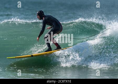 Ein Surfer, der ein Longboard beim Fistral in Newquay in Cornwall benutzt. Stockfoto
