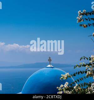 Detail eines blauen Kirchendachs auf Santorini Insel, Griechenland. Bougainvillea weiße Blüten im Vordergrund. Blaues Meer und Himmel im Hintergrund. Quadratisches f Stockfoto