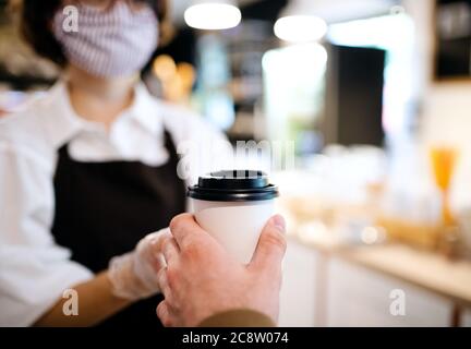 Nicht erkennbare Kellnerin mit Gesichtsmaske arbeitet im Café, Kunden zu bedienen. Stockfoto