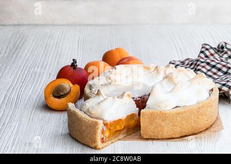 Leckere Meringuekuchen mit frischer Aprikose auf Holztisch Stockfoto