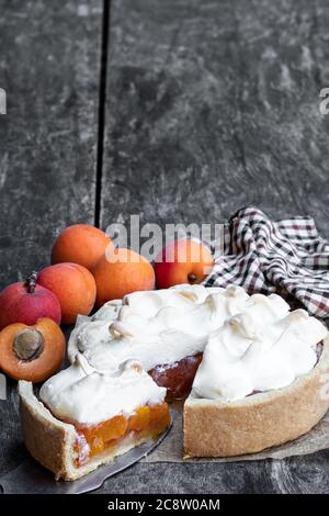 Leckere Meringuekuchen mit frischer Aprikose auf Holztisch Stockfoto