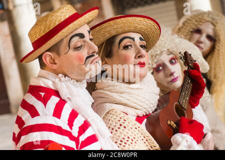VENEDIG, ITALIEN - 28. FEBRUAR 2020: Eine schöne Maskengruppe in Gondolierkostümen posiert mit einer Ukulele Stockfoto