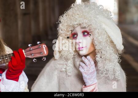 VENEDIG, ITALIEN - 28. FEBRUAR 2020: Eine Person mit weißem Make-up und weißer Perücke posiert und beobachtet einen Ukulelenhals Stockfoto