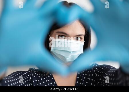 Nahaufnahme Porträt der Frau im Gesichtsmask zeigen Herzgesten Stockfoto
