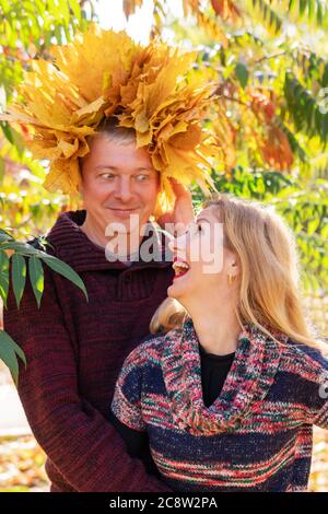 Lustiges Herbstporträt des Mannes mit einer Krone aus Blättern und einer lachenden Frau Stockfoto