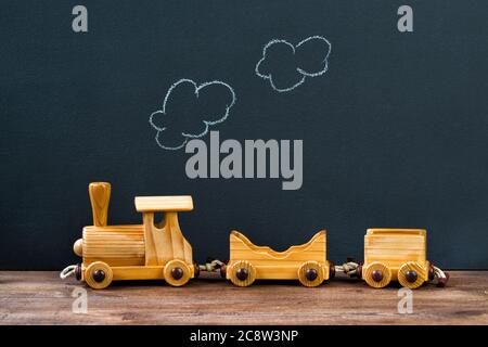 Alte hölzerne Spielzeugeisenbahn mit Dampf auf der Kreidetafel Hintergrund Stockfoto