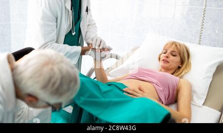 In dem Krankenhaus treibt die Frau in der Arbeit die Geburt voran, Geburtshelfer helfen Stockfoto
