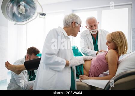 In dem Krankenhaus treibt die Frau in der Arbeit die Geburt voran, Geburtshelfer helfen Stockfoto