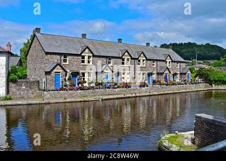 Eine terrassierte Reihe von hübschen Cottages am Kanalbecken des Monmouthshire & Brecon Canal. Blaue Türen und attraktive Blumen nach vorne. Stockfoto