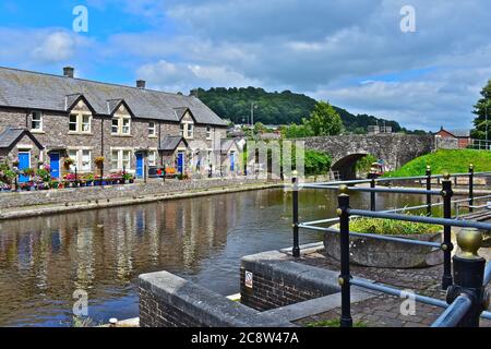 Eine terrassierte Reihe von hübschen Cottages am Kanalbecken des Monmouthshire & Brecon Canal. Blaue Türen und attraktive Blumen nach vorne. Stockfoto