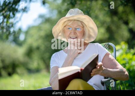 Aufgeregt ältere Frau Lesen eines interessanten Buches Stockfoto