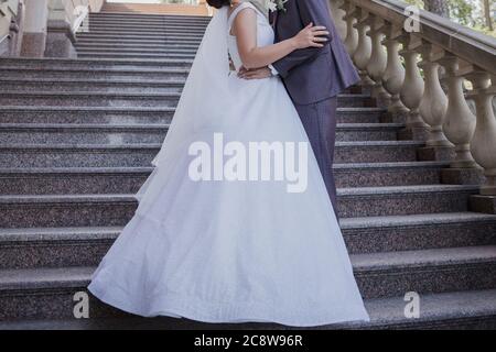 Bräutigam mit Braut auf der Treppe in der Nähe des Gebäudes Stockfoto