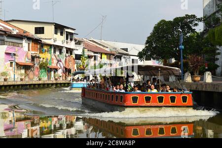 Schulkinder genießen das Kaleidoskop der hell gestrichenen Gebäude, die sich kilometerweit am Melaka River erstrecken. Stockfoto