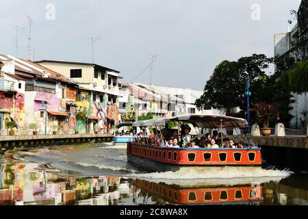 Schulkinder genießen das Kaleidoskop der hell gestrichenen Gebäude, die sich kilometerweit am Melaka River erstrecken. Stockfoto