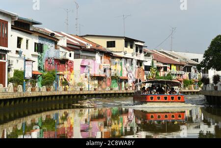 Schulkinder genießen das Kaleidoskop der hell gestrichenen Gebäude, die sich kilometerweit am Melaka River erstrecken. Stockfoto