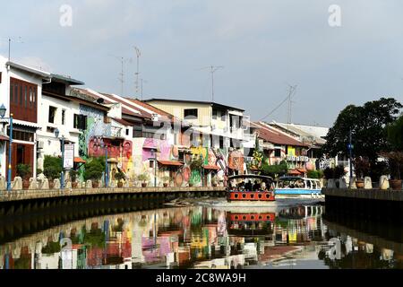 Schulkinder genießen das Kaleidoskop der hell gestrichenen Gebäude, die sich kilometerweit am Melaka River erstrecken. Stockfoto