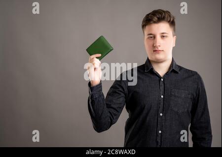 Portrait von ernst stilvolle attraktive Mann mit einem lässigen schwarzen Hemd zeigt Brieftasche isoliert auf grauem Hintergrund mit Kopie Raum Werbung ar gekleidet Stockfoto