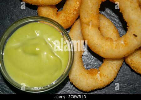 Zwiebelringe und ein Glas-Topf mit Sauce. Nahaufnahme Stockfoto