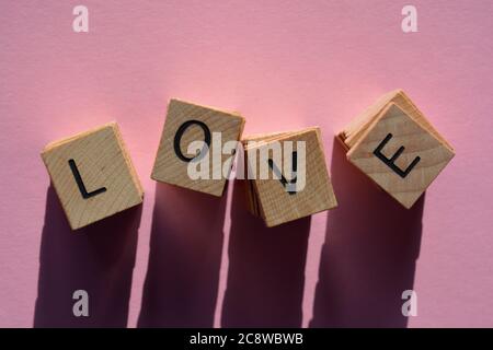 Liebe, Wort in Stapeln von 3d-Holz Alphabet Buchstaben isoliert auf rosa Hintergrund Stockfoto