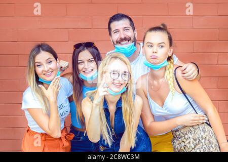 Glückliche junge Freunde, die Selfie mit offenen Gesichtsmasken machen lustige Gesichter Stockfoto