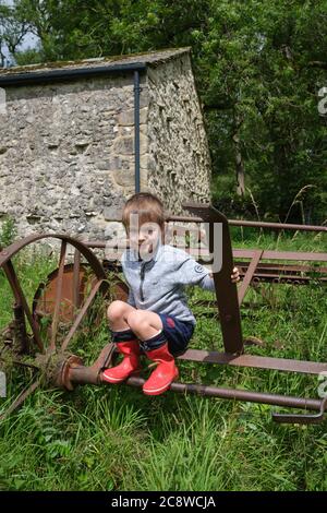 Ein vierjähriger Junge, der auf rostenden Bauernhöfen in Yorkshire Dales, Großbritannien, sitzt. Stockfoto