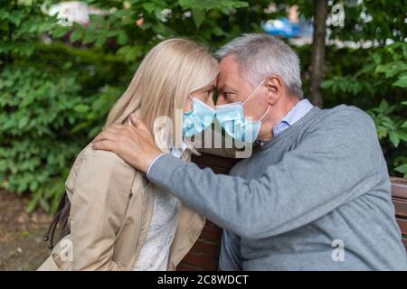 Reifes Paar umarmt in einem Park während Coronavirus Pandemie Stockfoto