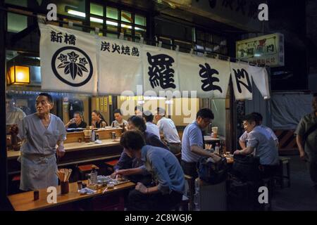 Essen unter den Bahngleisen: Die Yakitori Gasse, Tokyo Japan. Unter den Bahngleisen, durch die die berühmten Hochgeschwindigkeitszüge passieren, befindet sich diese Gasse, voll von kleinen lokalen und preiswerten Restaurants, in denen neben den typischen Hühnerspieße andere ungewöhnliche weniger häufig dieser Vögel wie Süßbrot, Leber, Herz, Darm und sogar Ihre Gebärmutter serviert werden. Weltweit eingesetzt Stockfoto