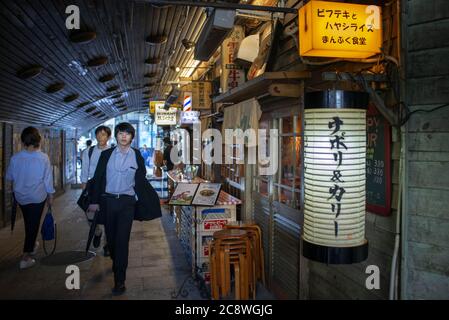 Essen unter den Bahngleisen: Die Yakitori Gasse, Tokyo Japan. Unter den Bahngleisen, durch die die berühmten Hochgeschwindigkeitszüge passieren, befindet sich diese Gasse, voll von kleinen lokalen und preiswerten Restaurants, in denen neben den typischen Hühnerspieße andere ungewöhnliche weniger häufig dieser Vögel wie Süßbrot, Leber, Herz, Darm und sogar Ihre Gebärmutter serviert werden. Weltweit eingesetzt Stockfoto