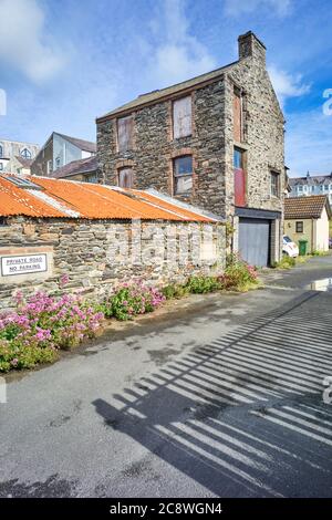 Ein ehemaliges Lagerhaus des Bauherrn, das sich in einem Zustand des Zerfalls und der Verrottung mit verfaulten Fenstern und Löchern in den Steinwänden befindet Stockfoto