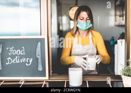 Junge Frau bereitet Lieferkost im Restaurant zum Mitnehmen während der Coronavirus-Ausbruch-Periode - Arbeiter in der Küche Kochen gesunde Lebensmittel für hom Stockfoto