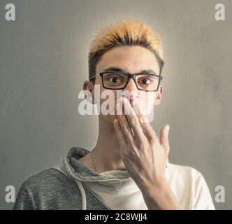 Ein Junge, der seine Hand vor seinen Mund legt Stockfoto
