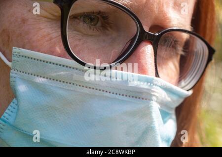 Frau trägt eine medizinische Maske in einem Garten Stockfoto