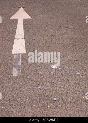 Asphaltstraße mit Pfeil und geknackten Kunststoffen von Autos Stockfoto