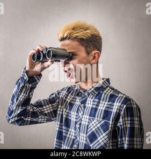 Junger Mann, Blick durch ein Fernglas Stockfoto